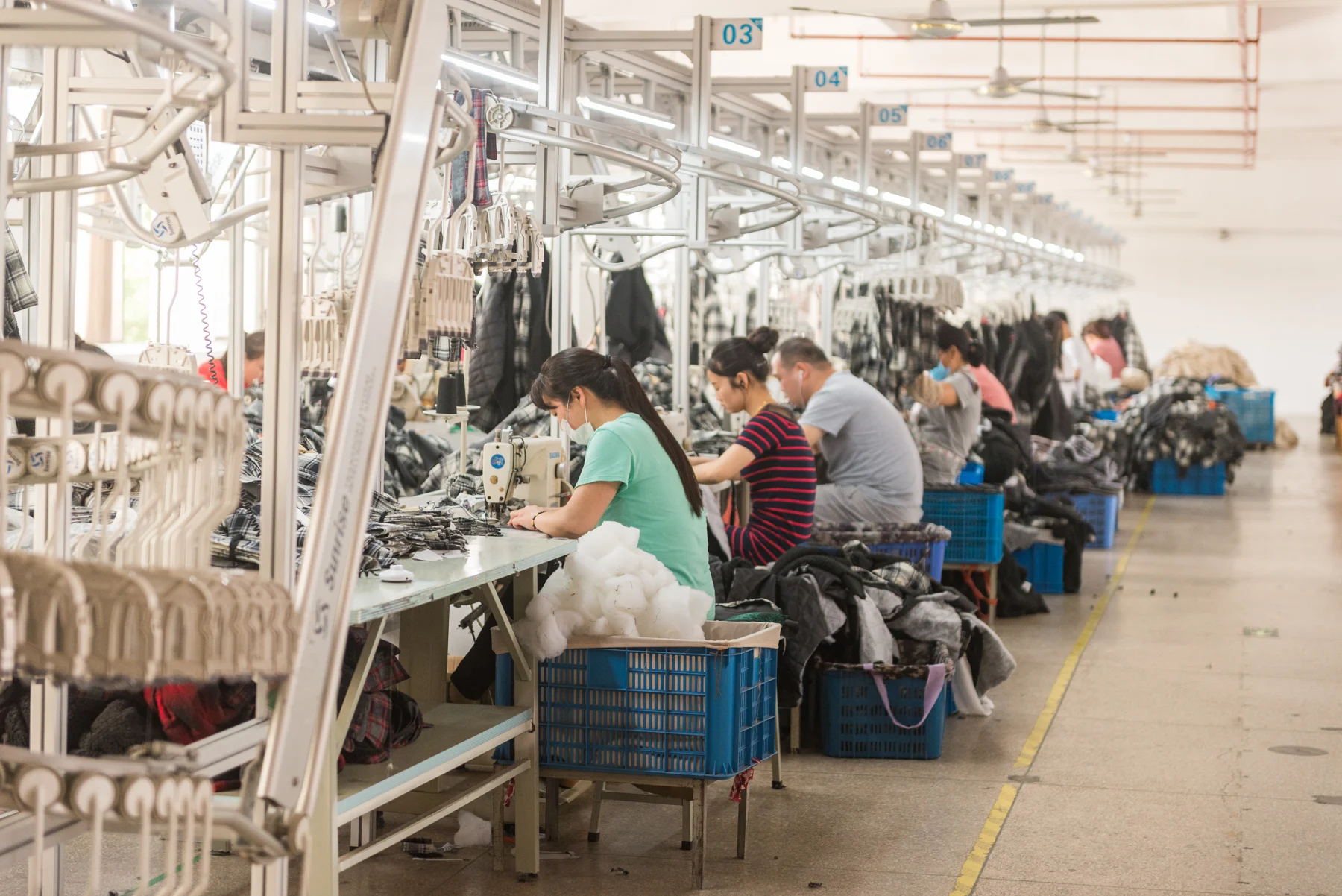 Workers sewing garments along a factory production line