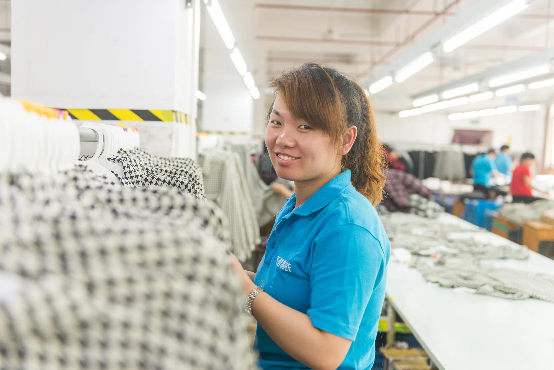 Garment worker standing beside patterned garments on hangers