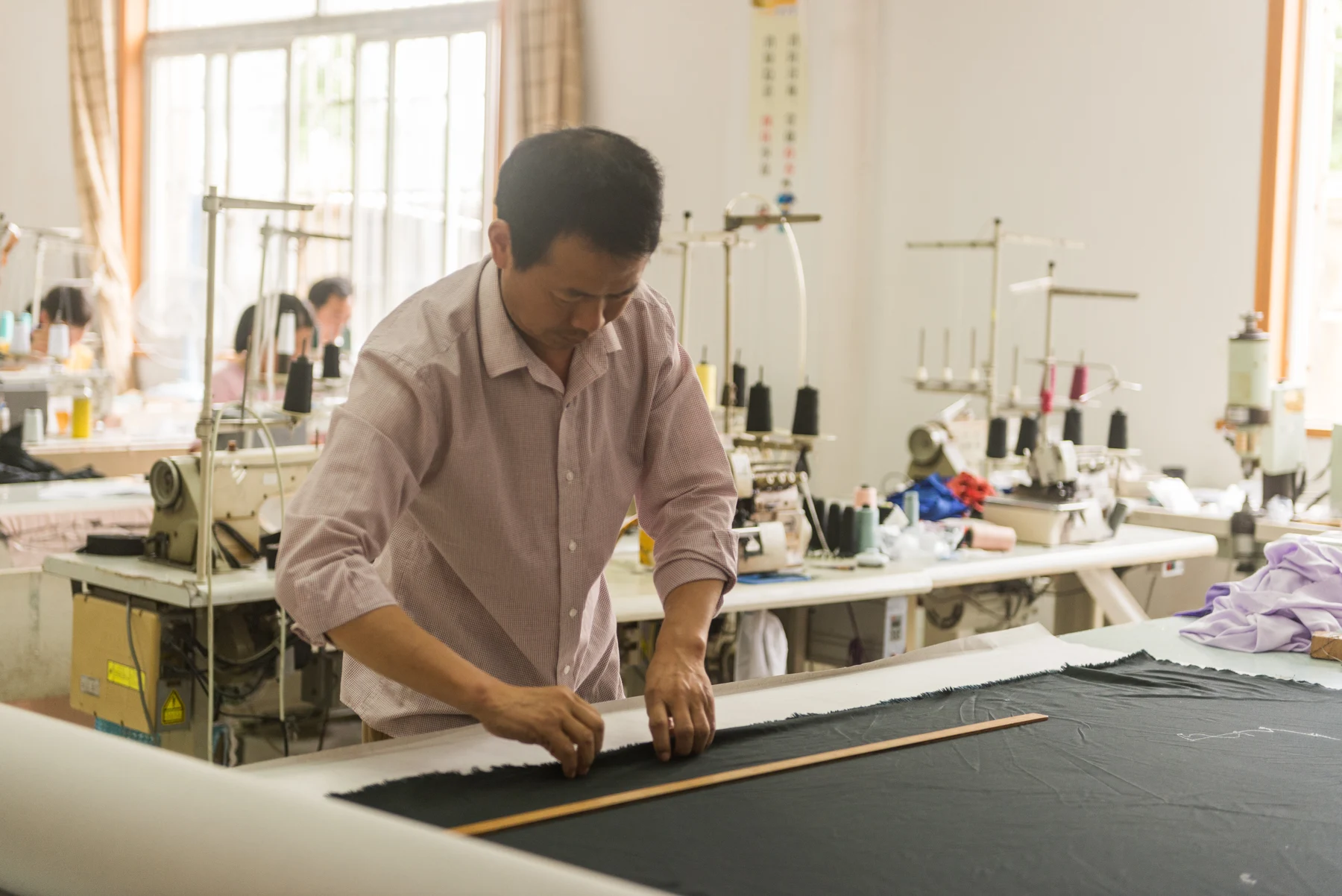 Sample maker marking dark fabric beside a ruler