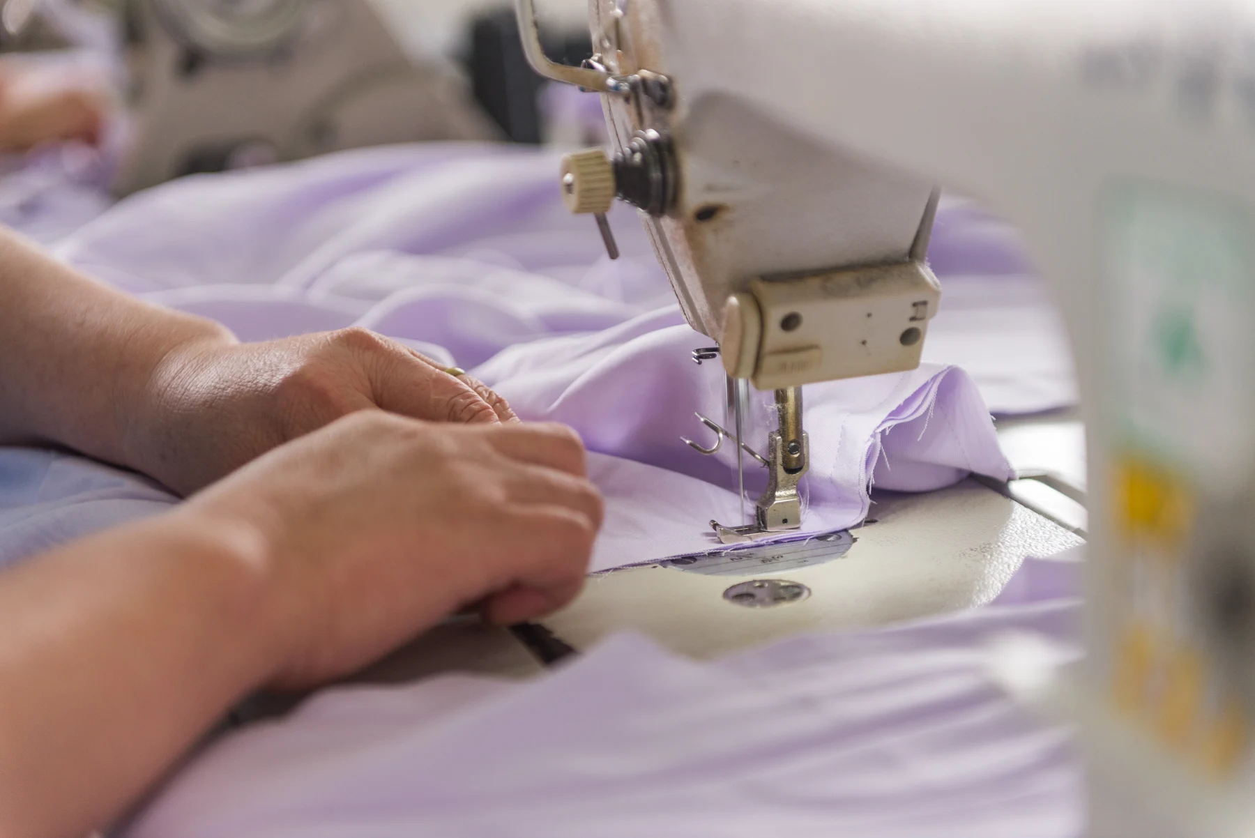 Sewing machine stitching a light purple garment